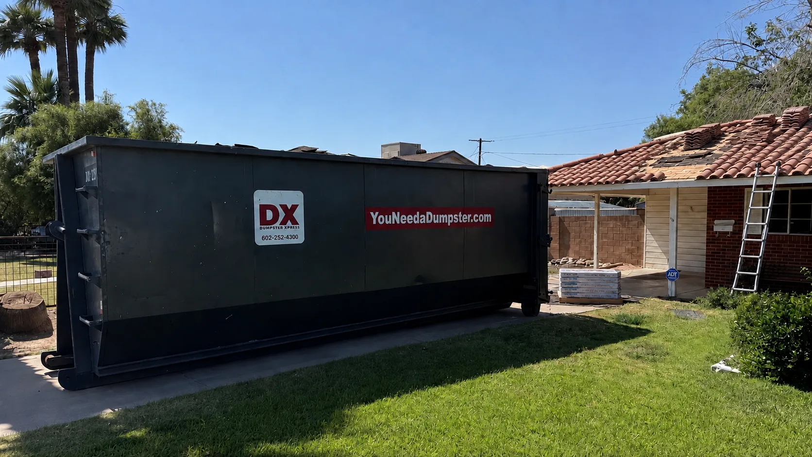 Dumpstr Xpress roofing dumpster beside a Phoenix home with a clay tile roof