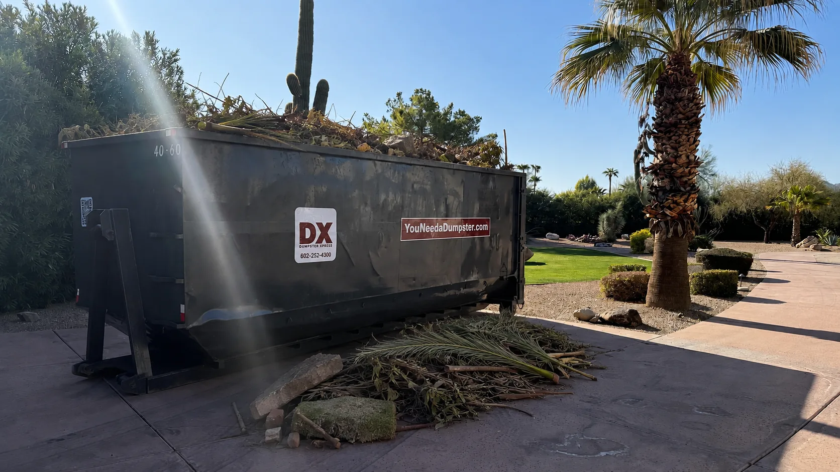 Dumpstr Xpress roll-off dumpster filled with landscaping debris at a Phoenix property
